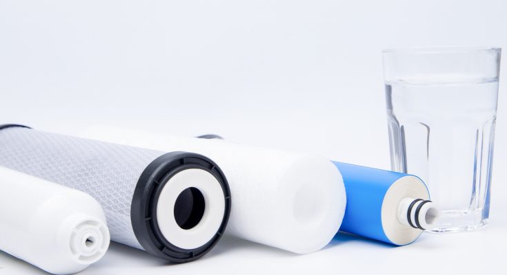 Filtereinsätze für Osmoseanlagen und ein Glas mit klarem Wasser